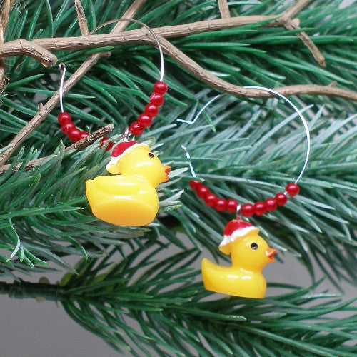 Yellow rubber duck Christmas earrings with red beads on a green branch.