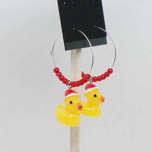 Earrings with rubber duck charms and red beads on a white background