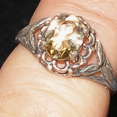 Silver ring with a yellow gemstone on a finger