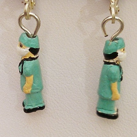 Earrings with green character charms on a light background