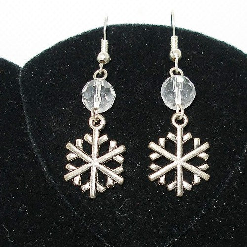 Silver snowflake earrings with clear beads on a black velvet background