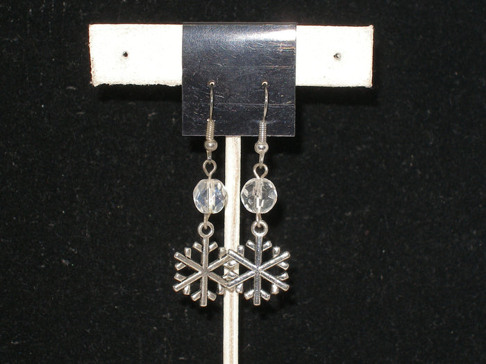 Silver snowflake earrings with clear crystals on a black background