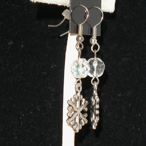 Silver earrings with snowflake and bead designs on a black background