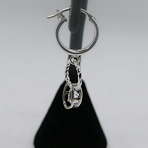 Silver hoop earring with a dangling gemstone charm on a gray background