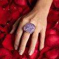photo of a models hand wearing an oversize silver amethyst slab ring on a bed of rose petals