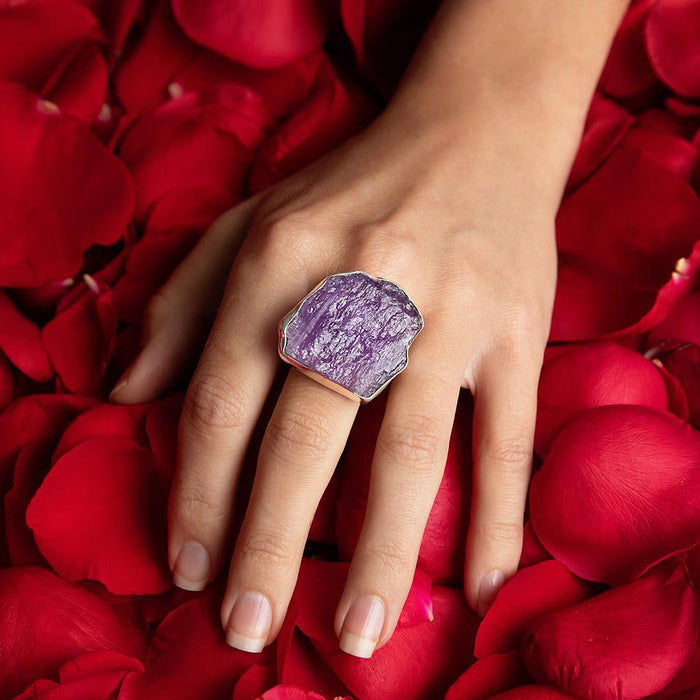 photo of a models hand wearing an oversize silver amethyst slab ring on a bed of rose petals