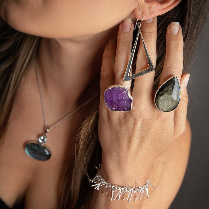 photo of a brunette model wearing an oversize silver amethyst slab ring with another ring and other jewelry