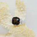 Silver ring with a smoky top stone on a textured beige surface