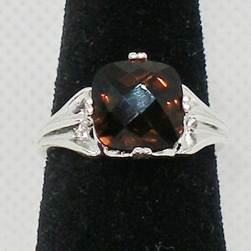 Ring with a large brown gemstone and silver band on a black stand.