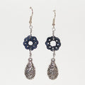 Pair of silver earrings with blue floral designs on a white background