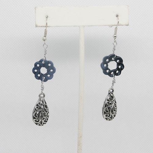 Pair of silver and blue floral earrings on a white stand