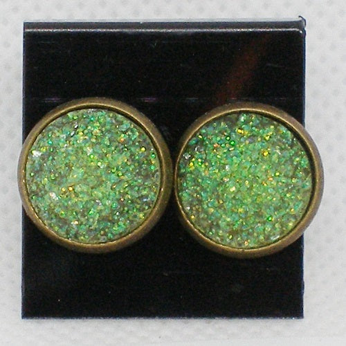 Green glittery round earrings with bronze setting on a black card.