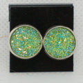 Pair of round earrings with green and blue glittery stones on a black background