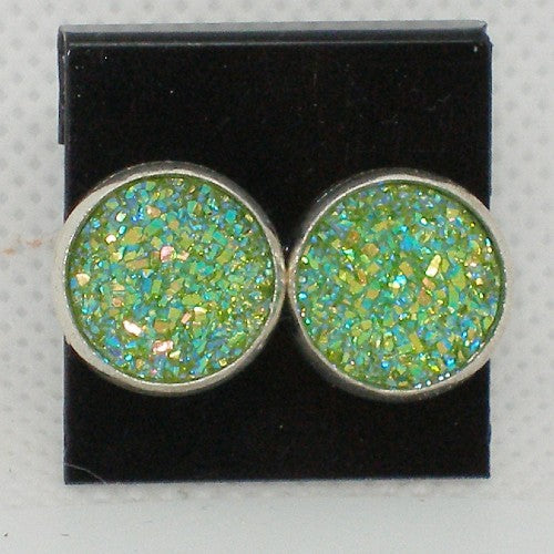 Pair of round earrings with green and blue glittery stones on a black background