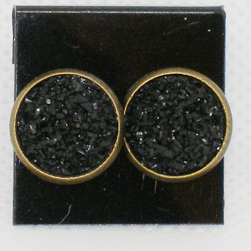Pair of round earrings with black textured centers and gold borders on a black card.