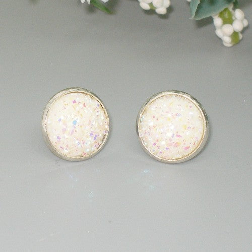 Round earrings with a glittery white center on a gray background