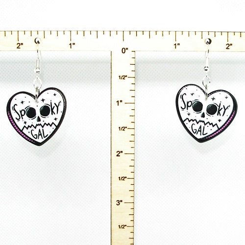Heart-shaped earrings with skull design and 'Spooky Gal' text next to a ruler for scale.