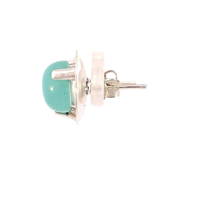 photo of silver earrings set with a blue chalcedony cabachon on a white background side view