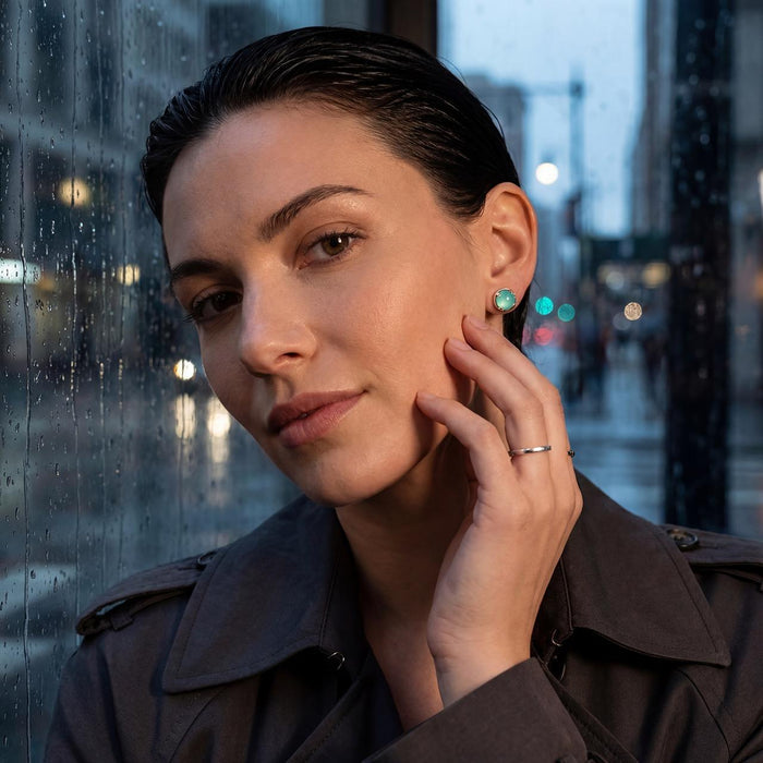photo of a brunette model wearing a silver earrings set with a blue chalcedony cabachon on an urban background