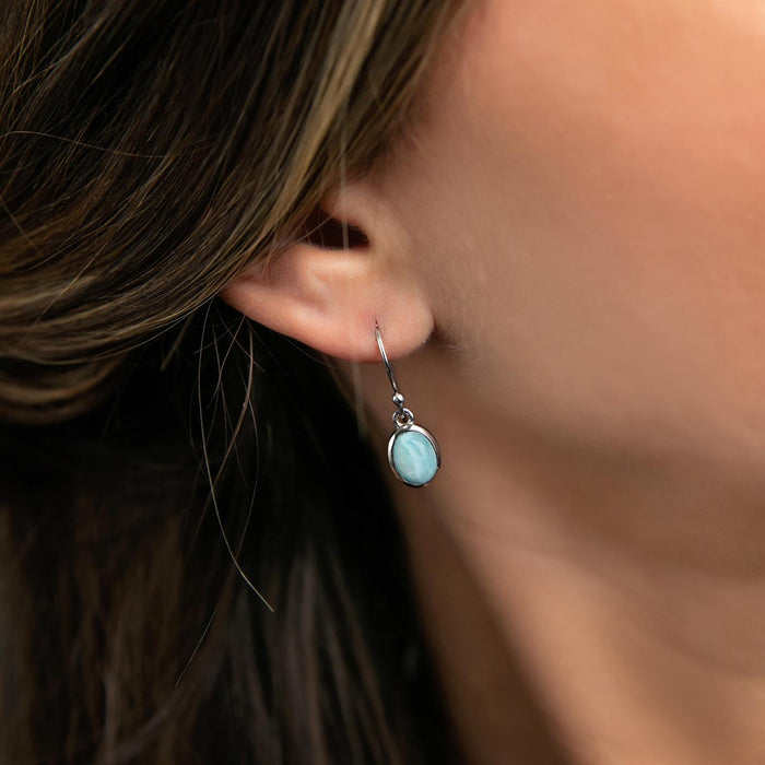 Photo of a brunette model wearing a silver earring set with oval cabochon blue Larimar