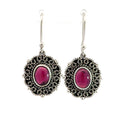 photo of a pair of oval silver filigree earrings set with an oval red garnet on a white background