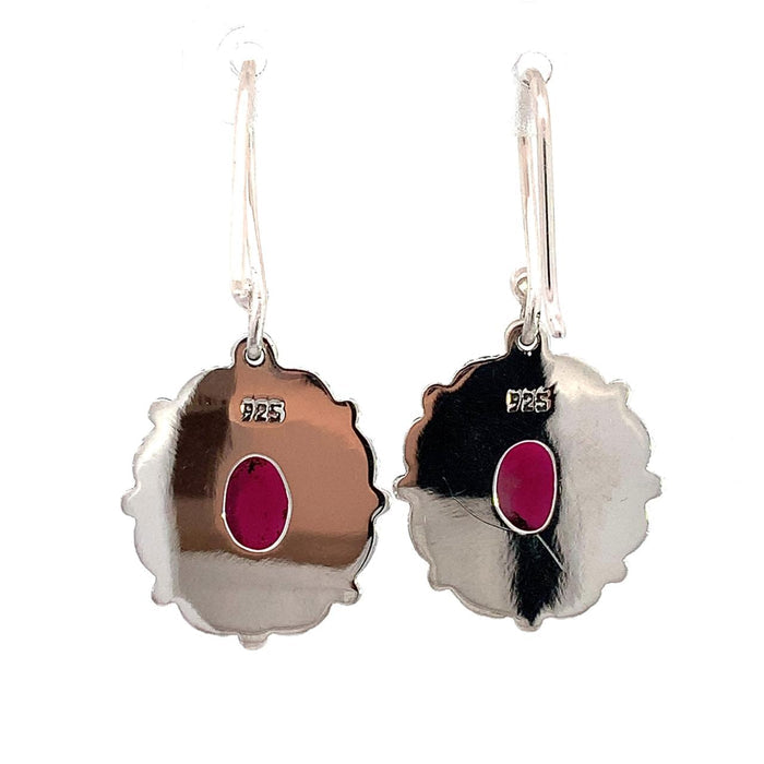 photo of a pair of oval silver filigree earrings set with an oval red garnet on a white background rear view