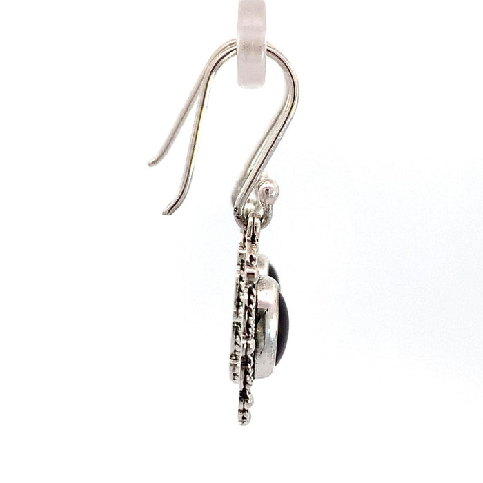 photo of a pair of oval silver filigree earrings set with an oval red garnet on a white background side view