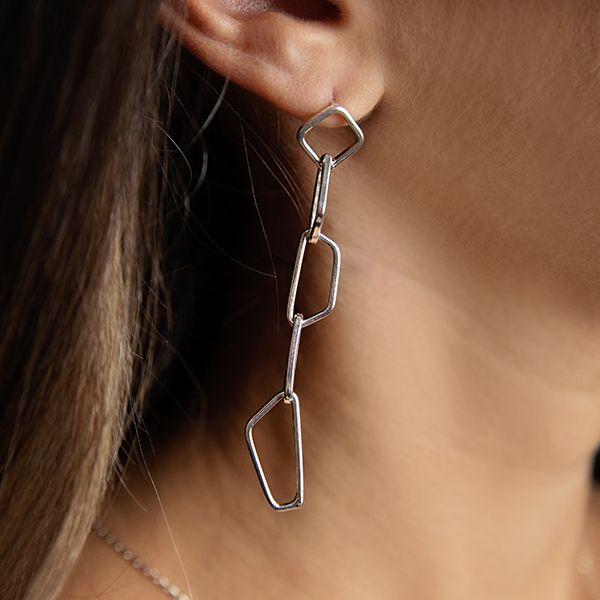 photo of a brunette model wearing a silver drop link style earring
