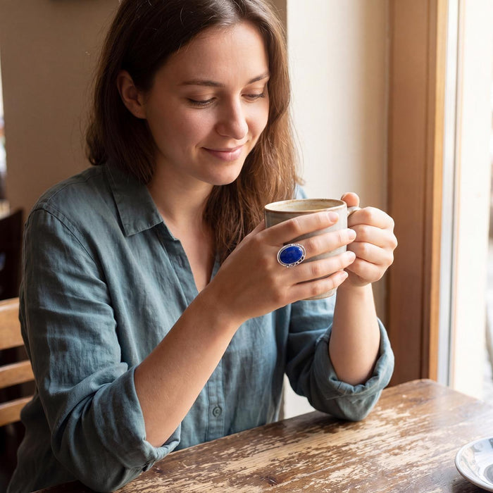 photo of a model wearing a Sterling Silver Lapis Ring featuring a large oval cabochon Lapis Lazuli set in a fine silver bezel-setting, with a scalloped edge design.