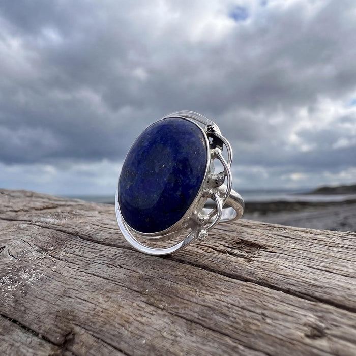 outdoor photo shot of A Sterling Silver Lapis Ring featuring a large oval cabochon Lapis Lazuli set in a fine silver bezel-setting, with a scalloped edge design.