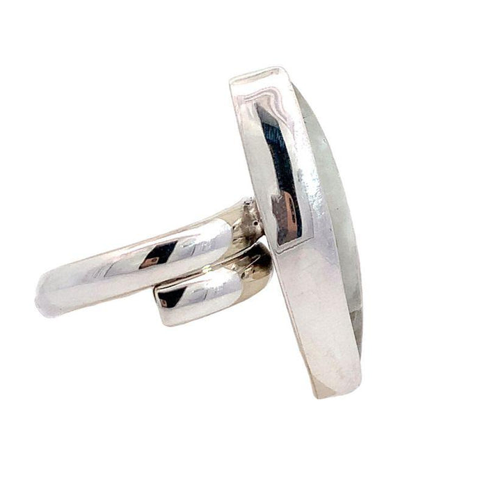 photo of a silver ring set with a long marquise moonstone on a white background side view