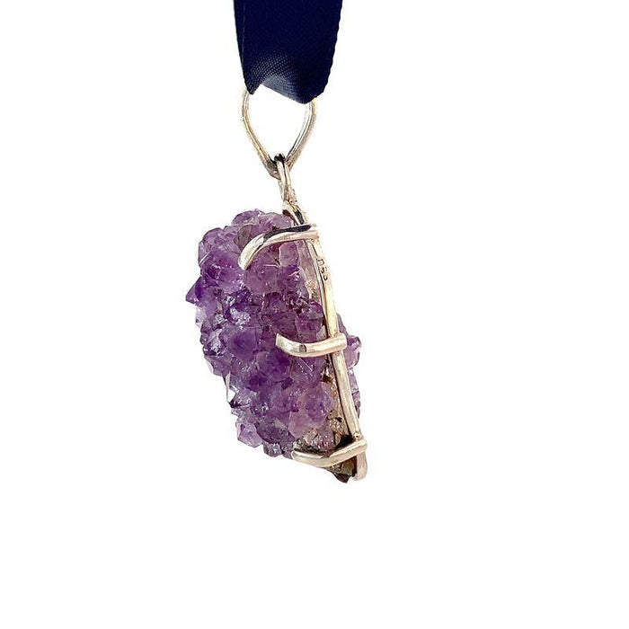 photo of a sterling silver amethyst druzy pendant on a ribbon on a white background side view