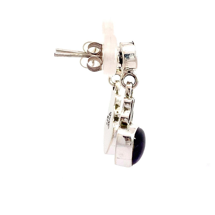 photo of a silver drop earring with a trillion cabochon amethyst bottom on a white background side view