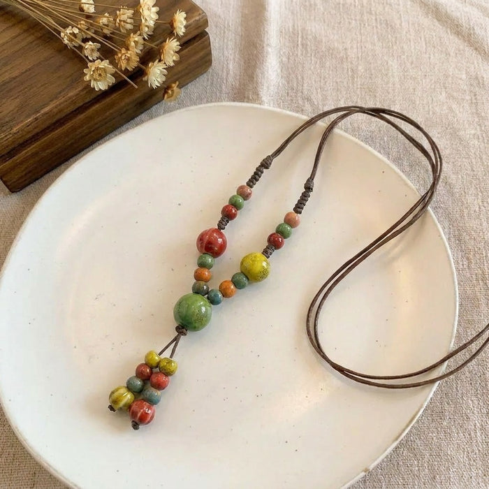 A cheerful blend of sunlit colors and handcrafted charm, this necklace features vibrant ceramic-style beads arranged on a natural cord for a playful boho look. Its bright red, green, yellow, and blue tones create a joyful statement that feels artistic, earthy, and effortlessly unique.