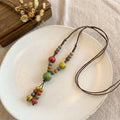 A cheerful blend of sunlit colors and handcrafted charm, this necklace features vibrant ceramic-style beads arranged on a natural cord for a playful boho look. Its bright red, green, yellow, and blue tones create a joyful statement that feels artistic, earthy, and effortlessly unique.