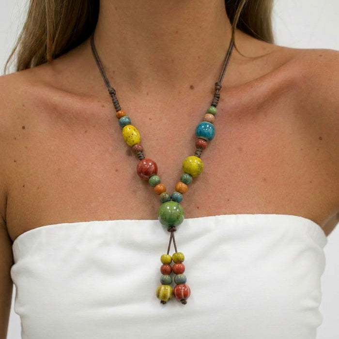 A cheerful blend of sunlit colors and handcrafted charm, this necklace features vibrant ceramic-style beads arranged on a natural cord for a playful boho look. Its bright red, green, yellow, and blue tones create a joyful statement that feels artistic, earthy, and effortlessly unique.