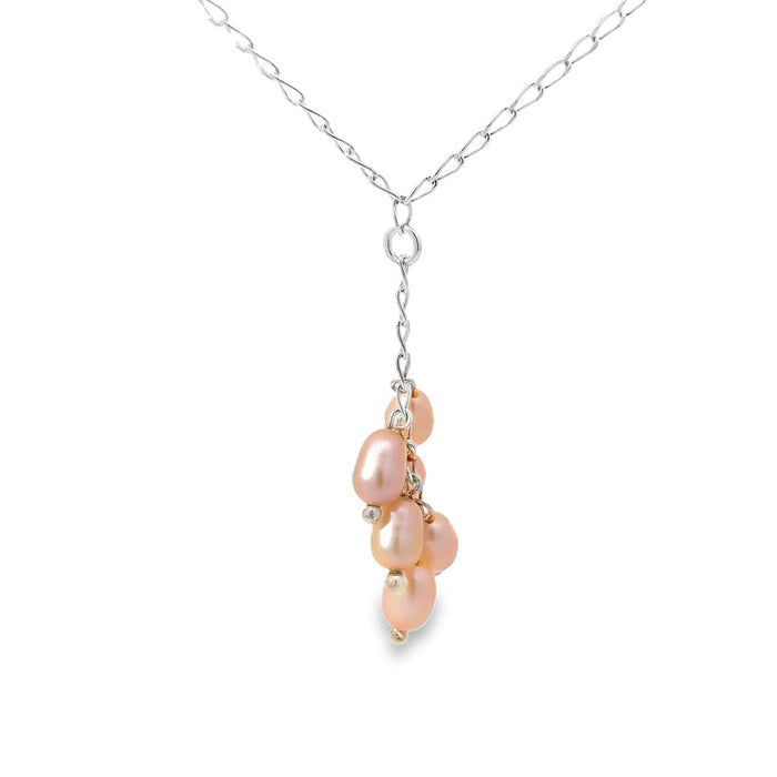 Photo of a cluster of peach colored pearls on a y shaped silver chain on a white background