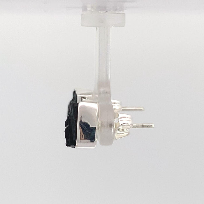 photo of a pair of silver square raw black tourmaline stud earrings on a white background side view