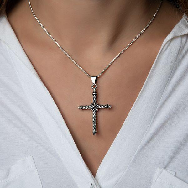Photo of a model wearing silver twisted wire cross pendant on chain