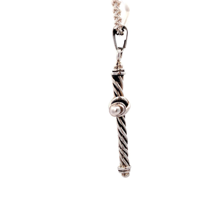 Photo of a silver twisted wire cross pendant on chain on a white background Side view