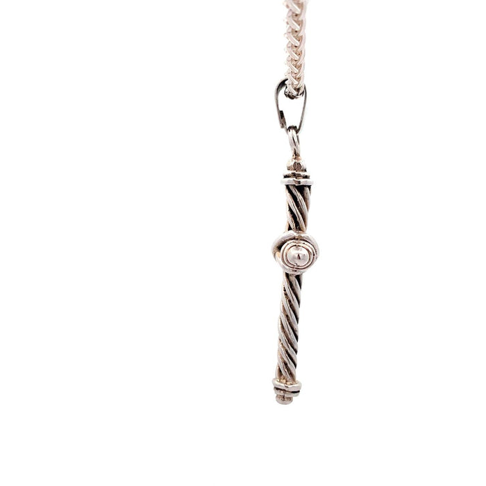 Photo of a silver twisted wire cross pendant on chain on a white background Side view
