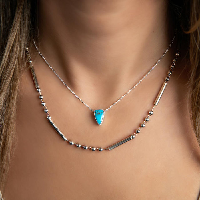 photo of a model wearing a silver bar and ball chain with a turquoise necklace