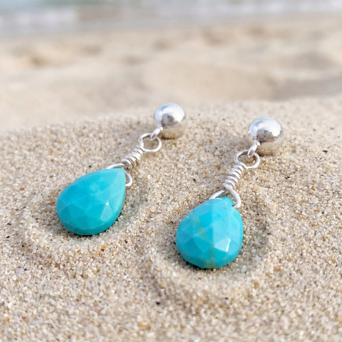 AI image of Sterling silver turquoise briolette dangle earrings handmade in Taxco Mexico laying on beach sand