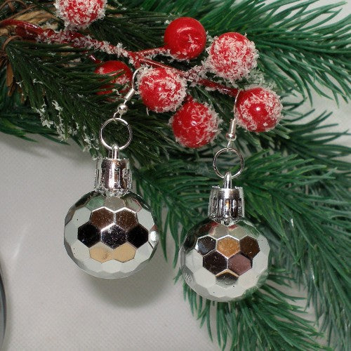 Silver faceted ball earrings with red berries on a green branch background