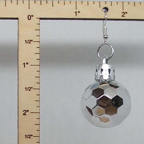 Silver disco ball earring with hexagonal design on a white background, next to a wooden ruler for scale.