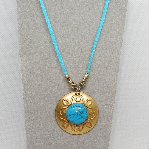 Necklace with brass pendant and turquoise stone on a light gray background