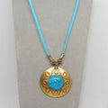 Necklace with brass pendant and turquoise stone on a light gray background