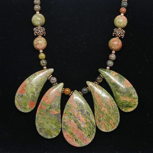 Necklace with green and brown teardrop-shaped beads on a black background