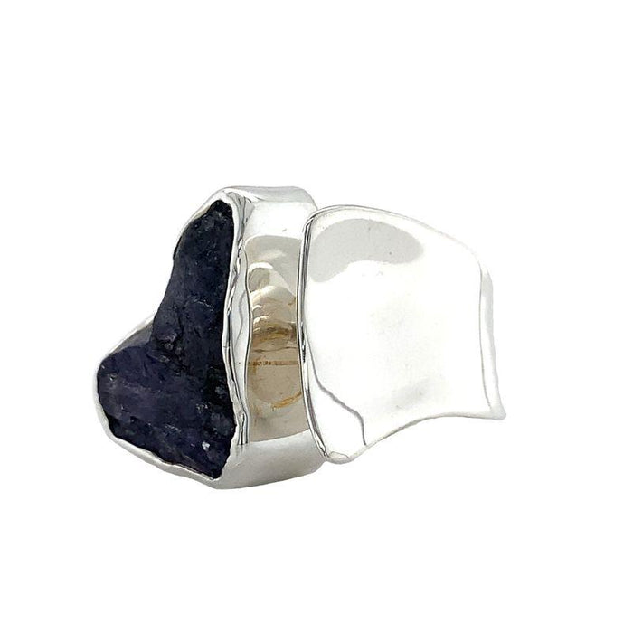 photo of a bold silver ring set with a raw irregularly shaped tanzanite on a white background front-side view