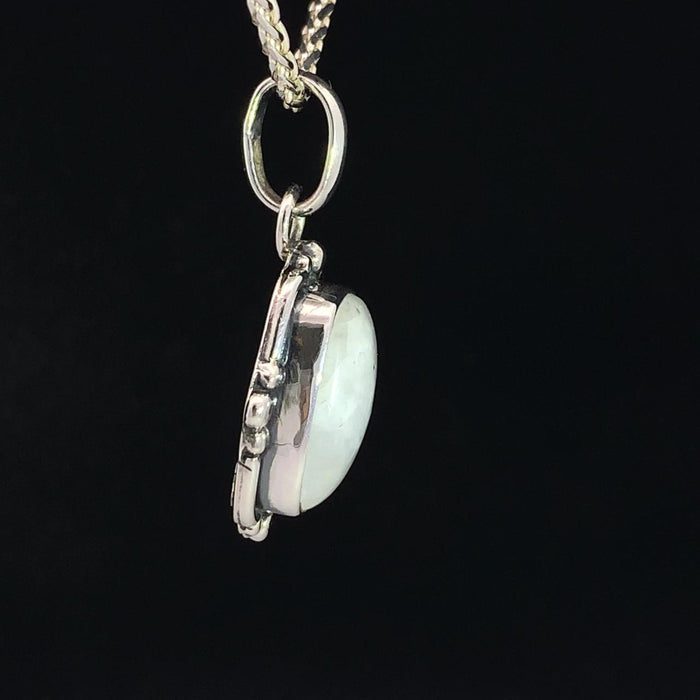 photo of a silver white moonstone pendant on a silver chain on a black background side view